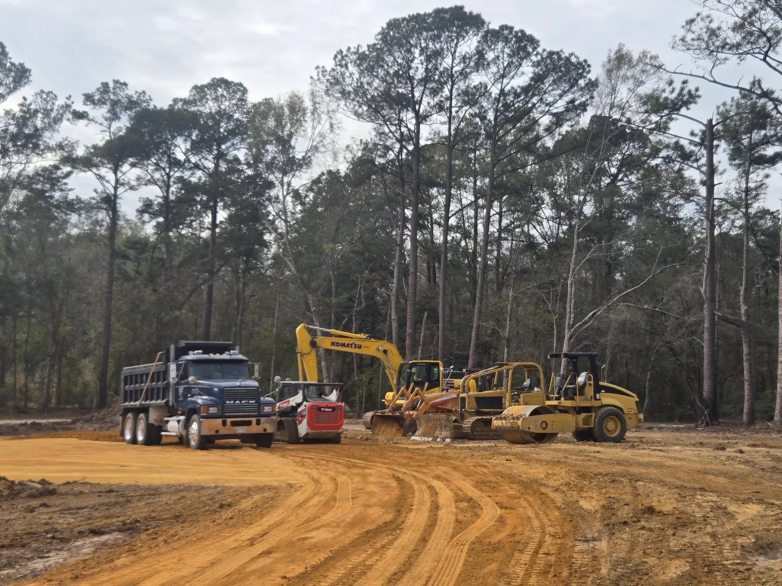 Dump truck excavator tracked loader and soil compactor on a worksite